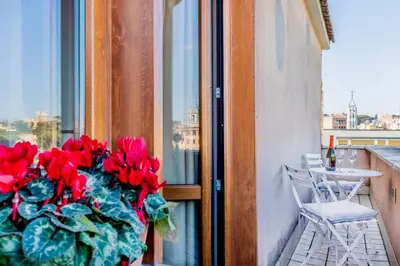 a window with a bunch of red flowers on a balcony at My San Pietro Home, Vaticano in Rome