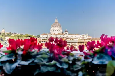 a bunch of red flowers in front of a building at My San Pietro Home, Vaticano in Rome
