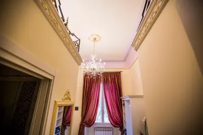 a chandelier and a window with red curtains at Trastevere Royal Suite Trilussa in Rome