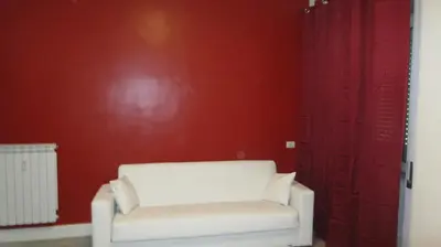 a living room with a white chair and red wall at Bed&bookofrome in Rome