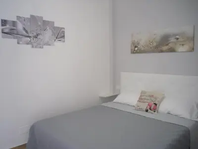 a bedroom with a bed with a gray blanket and a painting at Lovely Little Apartment in Via Aurelia in Rome