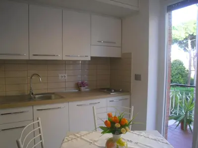 a kitchen with white cabinets and a table with a vase of flowers at Lovely Little Apartment in Via Aurelia in Rome