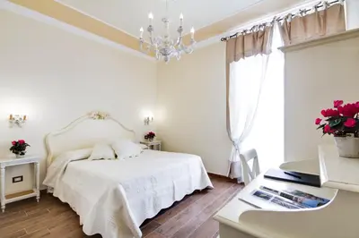 a white bedroom with a bed and a chandelier at Lunaria Suites Rome Vaticano in Rome