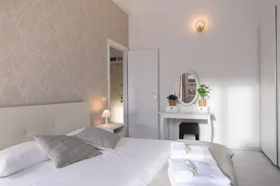 a bedroom with a white bed and a mirror at White Napoleone Apartment in Rome