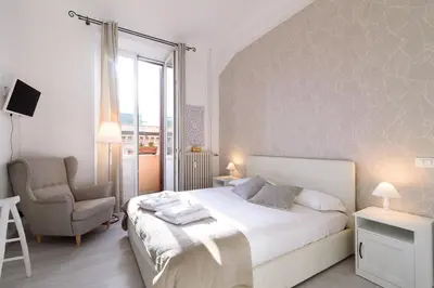 a white bedroom with a bed and a chair at White Napoleone Apartment in Rome