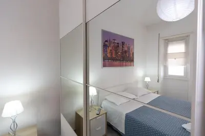 a white room with a bed and a mirror at Nicla's Home in Rome