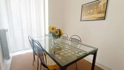 a glass table with chairs and a vase of sunflowers on it at Lovely 5 min walk to Saint Peter Basilica in Rome