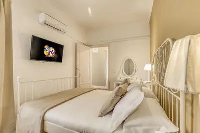 a white bedroom with a bed and a tv on the wall at ATRHOME penthouse Frattina in Rome
