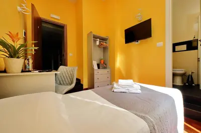a bedroom with a white bed and a yellow wall at Porta Pia Comfy Rooms in Rome