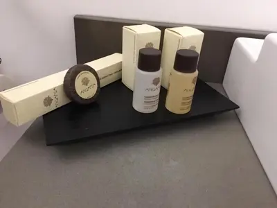 a shelf with three bottles of soap and a clock at Palazzo Lupardi Relais in Rome