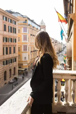 a woman standing on a balcony looking out over a city at Bespoke Roma Suites in Rome