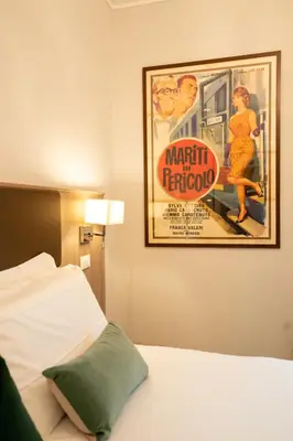 a poster for a movie hanging on a wall above a bed at Archi di Roma Guest House in Rome