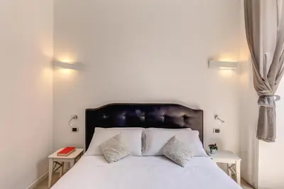 a bedroom with a white bed with two side tables at Manin Suites LT in Rome