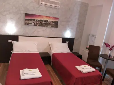 two beds in a room with red sheets and white towels at B&B A Home in Rome in Rome
