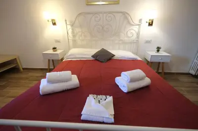 a bedroom with a large bed with red blanket and white pillows at Gialel Guesthouse in Rome