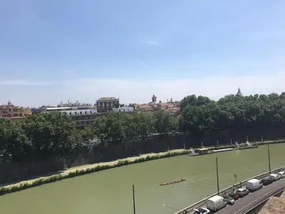 a river with cars parked on the side of a bridge at Modern Loft Walk to St Peter IREX Apartment in Rome