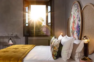 a bedroom with a bed with white pillows and a window at Palm Suites - Small Luxury Hotels of the World in Rome