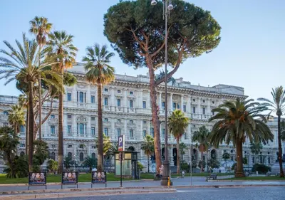 a large white building with palm trees in front of it at Ara Pacis Inn in Rome