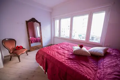 a bedroom with a pink bed with a mirror and a chair at Affittacamere Arte nei Colori in Rome