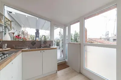 a kitchen with white cabinets and large windows at GuestHost - Piazza Venezia&Colosseum Loft in Rome