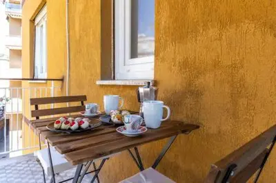 a table with cups and plates of food on a balcony at Romantic & Comfy Apartment Monteverde in Rome