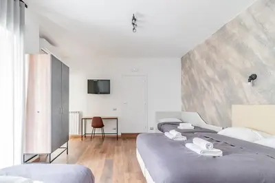 a bedroom with two beds and a tv on the wall at Luciano Licia Guest House in Rome