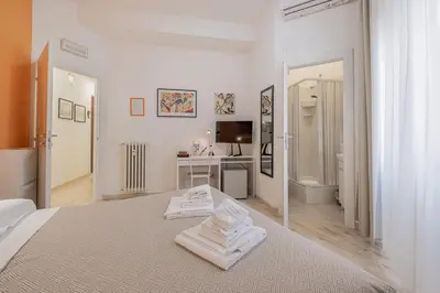 a white bedroom with a bed with towels on it at Damiani & Sister Guesthouse in Rome
