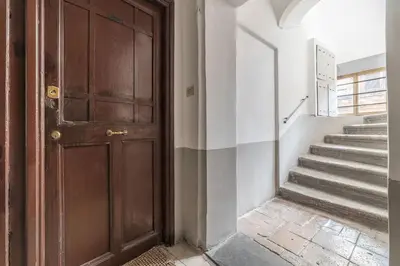 a hallway with a wooden door and stairs at GuestHost - Montecitorio & Pantheon Stylish Flat in Rome