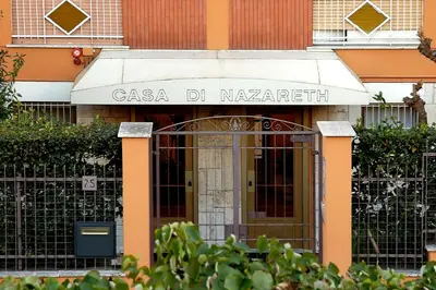 a gate in front of a building with a sign at La Casa di Nazareth in Rome