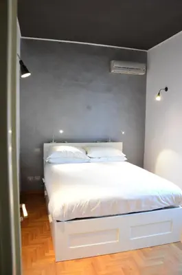 a bedroom with a white bed with a gray wall at Una finestra su Castel Sant'Angelo in Rome