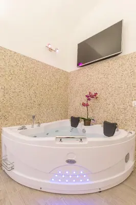a white tub in a room with a tv on the wall at Suite House Vaticano in Rome