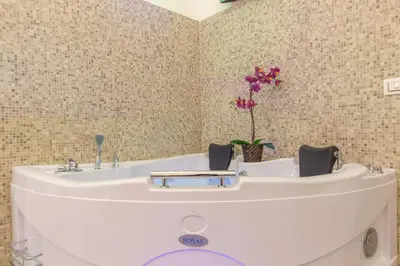 a bathroom with a tub with a table and purple flowers at Suite House Vaticano in Rome