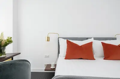 a bed with orange and white pillows and a chair at Maison Ottavia in Rome