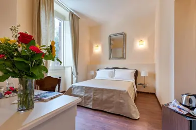 a bedroom with a bed and a vase of flowers on a table at Vatican Domus Smart Rooms in Rome