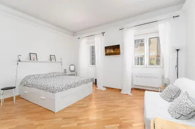 a white bedroom with a bed and a couch at La casa di Effe in Rome