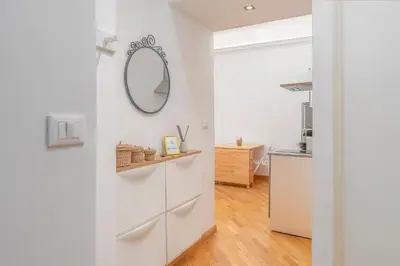 a white hallway with a mirror and a door at La casa di Effe in Rome