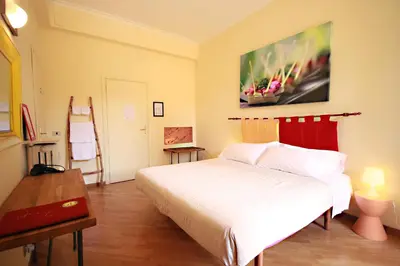 a bedroom with a white bed and a painting on the wall at The Beehive Hostel in Rome