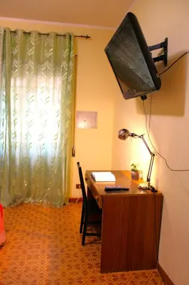 a room with a desk with a television and a table with a lamp at Roma Tiberius Suite in Rome