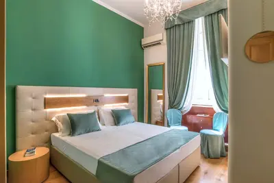 a bedroom with a bed with green walls and a chandelier at Hotel Paba in Rome