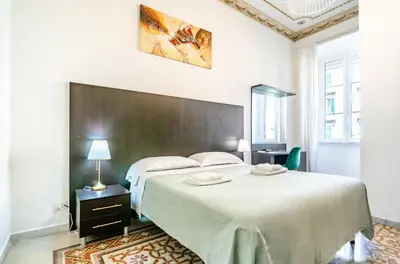 a white bedroom with a large bed and a table at El Dorado Colosseum in Rome