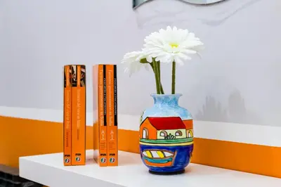 a flower in a blue vase next to books at TRIDENTE Apartment in Rome