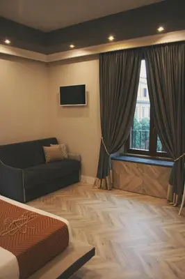 a bedroom with a bed and a couch and a window at Hotel Roma Vaticano in Rome