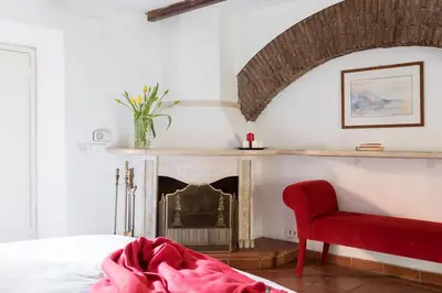 a bedroom with a red chair and a fireplace at Cedro Terrace&Jacuzzi - Loft in Trastevere in Rome