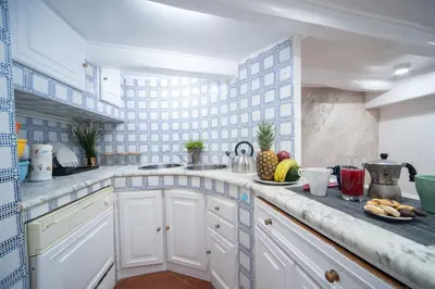 a kitchen with white cabinets and blue and white tiles at Navona Jacuzzi Apartment in Rome