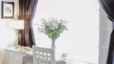 a vase of white flowers sitting on a table with a chair at Residenza Scipioni Luxury B&B in Rome