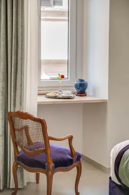 a chair with a purple cushion sitting next to a window at Adrianus Hotel in Rome