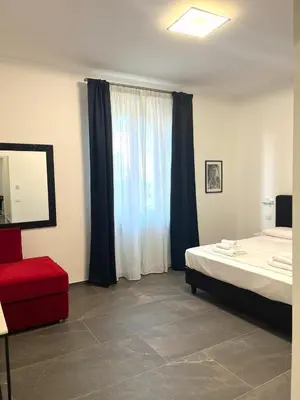 a bedroom with a bed and a red chair and a window at Inn Urbe Colosseo in Rome