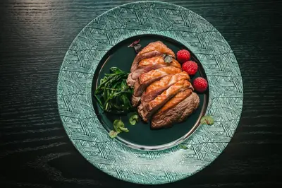 a plate with a steak and strawberries on a table at Tree Charme Parliament Boutique Hotel in Rome