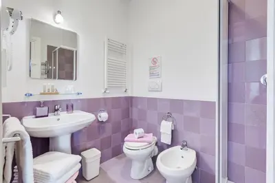 a purple and white bathroom with a sink and a toilet at 2 Passi Al Colosseo B&B in Rome