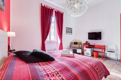 a bedroom with a bed with red curtains and a tv at 2 Passi Al Colosseo B&B in Rome